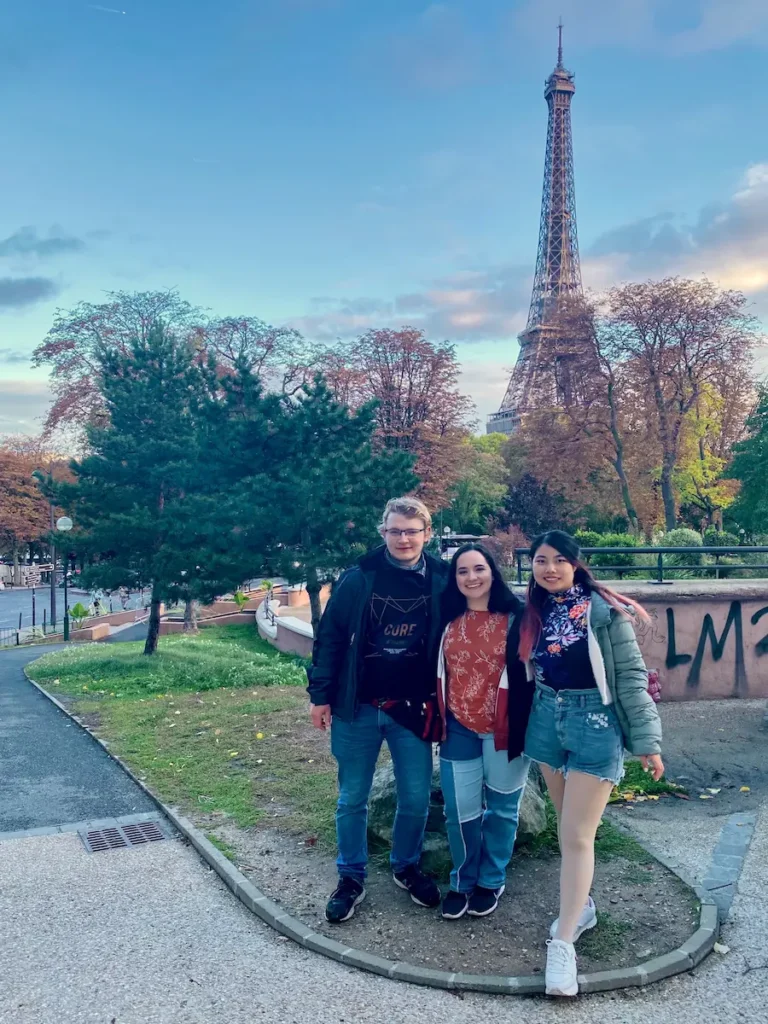 Travelers posing near the Eiffel Tower in Paris, showing how solo travel often leads to making new friends.