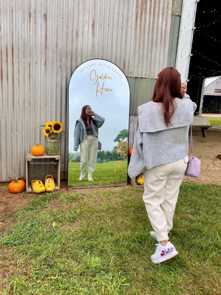 Visitor posing at the Golden Hour mirror photo station at Holland Ridge Farms Sunflower Festival.