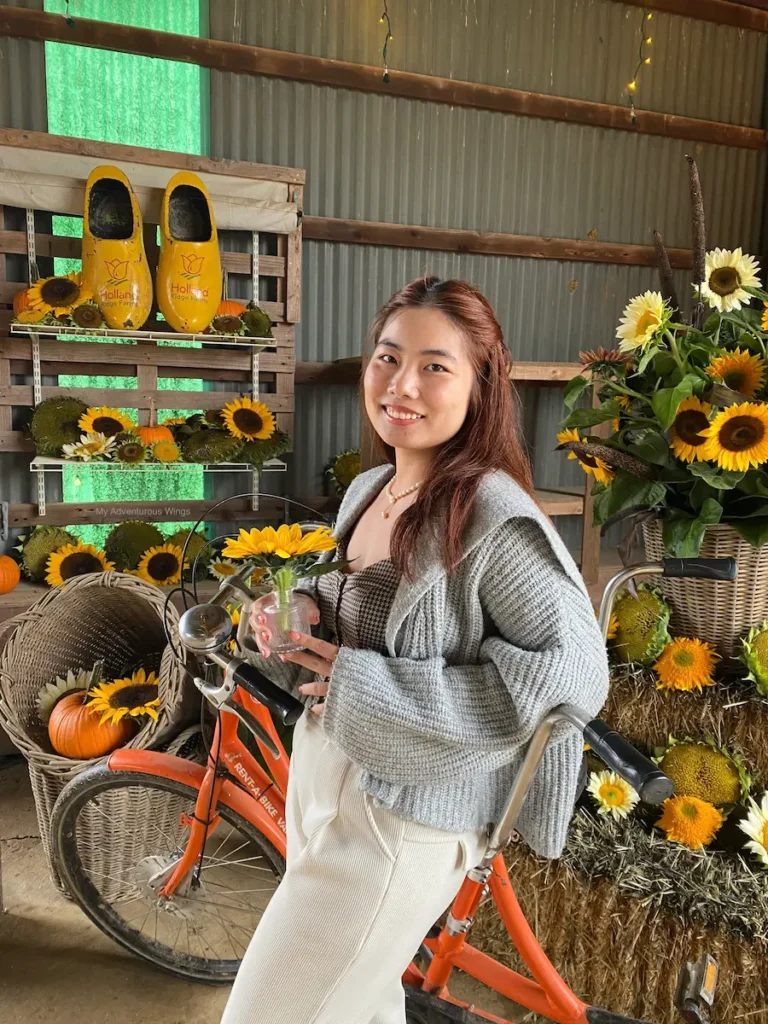 Guest posing with a sunflower bouquet by a tandem bike at Holland Ridge Farms Sunflower Festival.