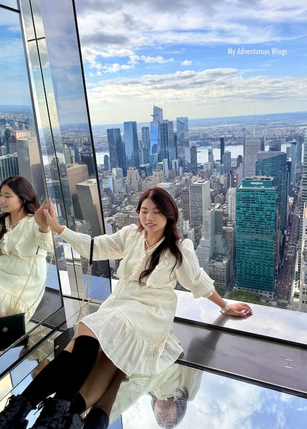 girl sitting on the floor at the summit observatory in nyc with a great view of the city down below